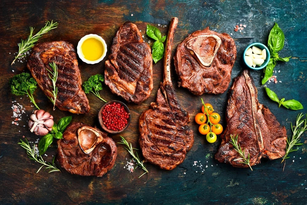 Grilled Angus steaks, tomahawk, garlic, herbs and tomatoes on a rustic wooden board